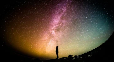greg-rakozy-oMpAz-DN-9I-unsplash Person standing under a starry night sky.