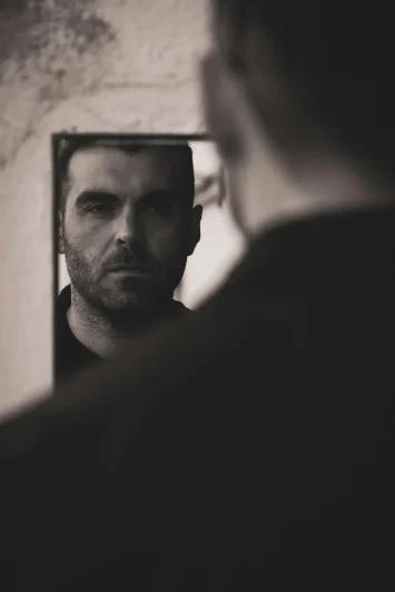 Man looking at his reflection in a mirror.